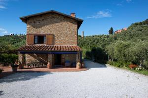 a large stone building with a porch on a hill at Villa La Pianella in Massarosa