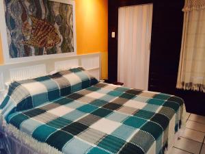 ein Schlafzimmer mit einem Bett mit einer karierten Decke in der Unterkunft Pousada Algas Marinhas in Fernando de Noronha