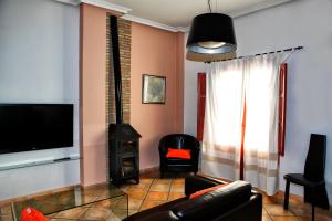 sala de estar con TV, sofá y chimenea en Hotel Rural El Molino de Felipe, en Mula