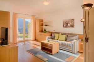 Una sala de estar con un sofá y un televisor en Appartment Maria, en Scena