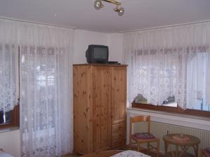 Zimmer mit einem TV auf einem Holzschrank mit Fenstern in der Unterkunft Hotel Panoramacafé Kattenes in Kattenes