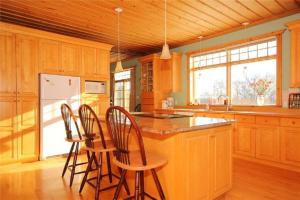 a kitchen with wooden cabinets and a island with bar stools at Rock Hill Bed & Breakfast in Sharbot Lake