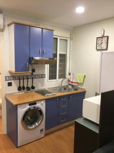 uma cozinha com uma máquina de lavar roupa e armários azuis em Casas de Sevilla - Estudio Peral 55 em Sevilha