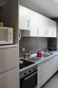 una cocina con armarios blancos y fregadero en A Primeira Casinha do Mé-Mé, en Manteigas