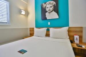 a bedroom with a large white bed with a blue wall at Mega Moda Goiania Hotel in Goiânia