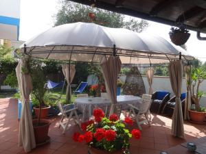 a patio with an umbrella and a table and flowers at La villa dell'ammiraglio in Forte dei Marmi