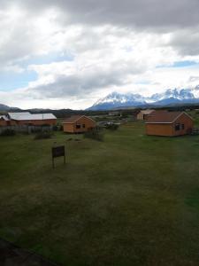 a field with houses and mountains in the background at Cabañas Lago Tyndall in Torres del Paine