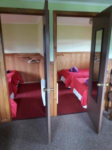 a bedroom with two beds with red sheets at Cabañas Lago Tyndall in Torres del Paine