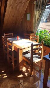 a wooden table with two chairs and a table and a table and chairs at Cabañas Orillas del Lago in Pucón
