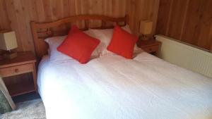 1 dormitorio con 1 cama con 2 almohadas rojas en Cabañas Orillas del Lago, en Pucón