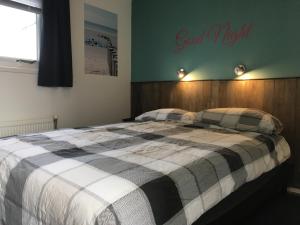 1 dormitorio con 1 cama con manta a cuadros en Chalet Zeester J38 Ameland, en Buren