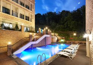 a swimming pool with stairs and chairs next to a building at Hotel Thesoom Forest in Yongin