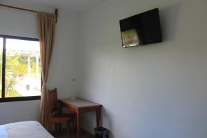 Cette chambre comprend un lit, un bureau et une télévision murale. dans l'établissement Real Primaveras Campestre, à Escárcega