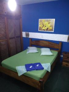 1 dormitorio con cama verde y pared azul en Pousada Costa Verde, en Caraguatatuba