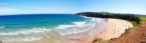 a group of people walking on a beach next to the ocean at Apartamentos Playa Galizano in Galizano