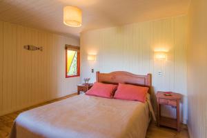 a bedroom with a large bed with two pink pillows at Cabañas Cantomar in Pichilemu