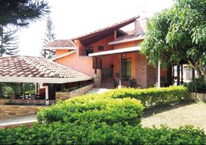 a house with a yard with trees and bushes at Hotel Cristo Rey Campestre in Los Santos