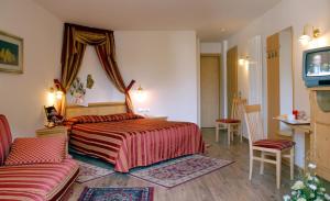 a bedroom with a bed and a couch and a tv at Hotel Sass Maor in Fiera di Primiero