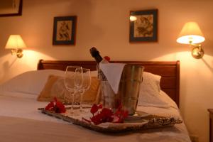 uma bandeja com uma garrafa de vinho e copos numa cama em Hotel Pousada Esmeralda em Itatiaia