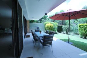 une terrasse avec une table, des chaises et un parasol dans l'établissement La Mer Holiday Apartments, à Mooloolaba