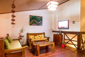 sala de estar con muebles de madera y TV de pantalla plana en Alto do Aeroporto Hotel en Porto Seguro