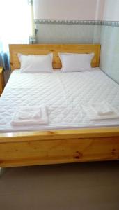 ein Holzbett mit weißer Bettwäsche und Kissen darauf in der Unterkunft Y Thu Guesthouse in Phu Quoc