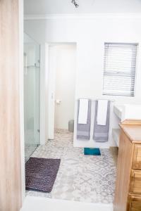 a bathroom with a shower and a sink and a mirror at Lemon Tree House in Plettenberg Bay