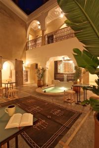 a living room with a table with books and a pool at Riad Dar Ten in Marrakesh