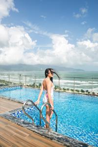 a woman walking down a hand rail in a swimming pool at Halina Hotel and Apartment in Da Nang