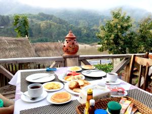 una mesa con platos de comida y un jarrón en BKC villa en Muang Pakbèng