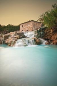 マンチャーノにあるterme di saturnia vacanzeの滝のある川の中の建物