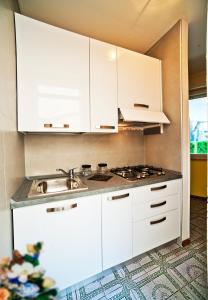 a kitchen with white cabinets and a sink at Olimpia in Bibione