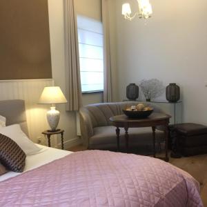 Un dormitorio con una cama, un sofá y una mesa. en Kirisavan Bed&Breakfast, en Borgloon