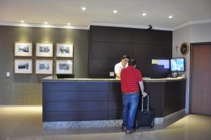 ドウラドスにあるHotel Valenciaのホテルのカウンターに立つスーツケースを持つ男