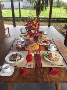 a table with plates of breakfast food on it at Cokelat Guest House in Tanah Lot