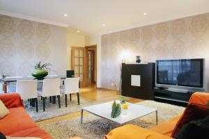 uma sala de estar com um sofá, uma mesa e uma televisão em Casino Lisboa House Apartment em Lisboa