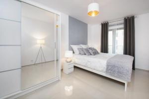 biała sypialnia z łóżkiem i szklaną ścianą w obiekcie Icon Apartments Centrum 55m2 we Wrocławiu