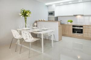 biała kuchnia z białym stołem i krzesłami w obiekcie Icon Apartments Centrum 55m2 we Wrocławiu