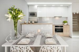 una cucina bianca con tavolo da pranzo e sedie di Icon Apartments Centrum 55m2 a Breslavia
