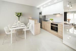 ヴロツワフにあるIcon Apartments Centrum 55m2の白いキッチン(テーブル、白い椅子付)