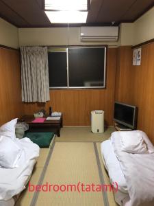 a room with two beds and a flat screen tv at Kenroku Haitsu 101 in Kanazawa