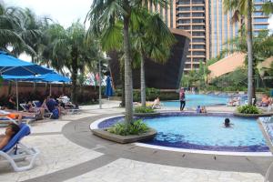 una piscina in un resort con persone su sedie e palme di FnF Suite @ Time Square a Kuala Lumpur