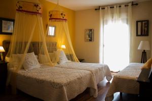 1 dormitorio con 2 camas, cortinas y ventana en Casa Rural Alquería de Segovia, en Tizneros