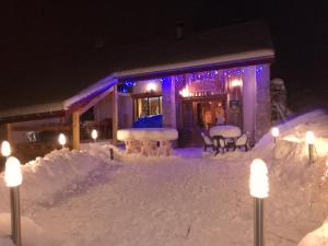 una casa cubierta de nieve por la noche con luces en La Grange De L'Errance en Giron