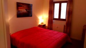 Un dormitorio con una cama roja y una ventana. en Appartement la Charbonnière, en Bellefosse