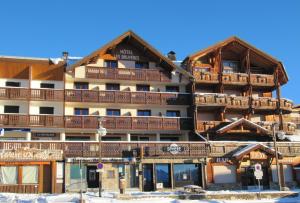 un gran edificio con balcones de madera en la nieve en Hotel Les Bruyères, en L'Alpe-d'Huez