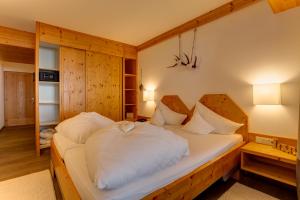 una camera da letto con un grande letto con lenzuola bianche di Am Dorfplatz Suites - Adults only a Sankt Anton am Arlberg