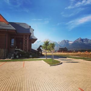 a large building with mountains in the background at Vila Mlynica in Veľká Lomnica