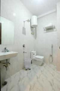 a white bathroom with a toilet and a sink at Hotel Chanakya inn in New Delhi +25 photos