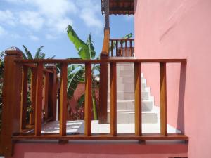 un balcón de madera con escaleras en una casa rosa en Flores de Búzios Suítes en Búzios